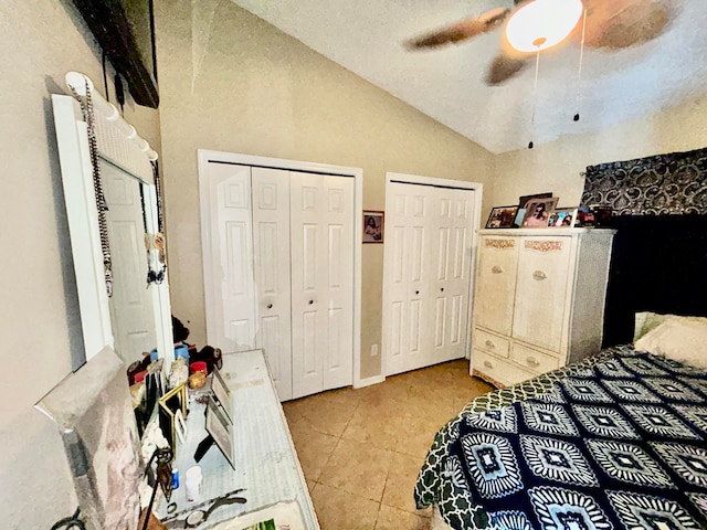 bedroom with tile patterned floors, lofted ceiling, ceiling fan, and two closets