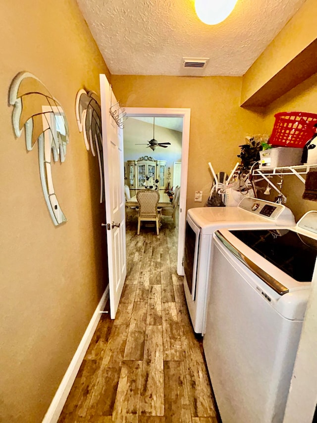 laundry room featuring wood-type flooring, washing machine and dryer, a textured ceiling, and ceiling fan