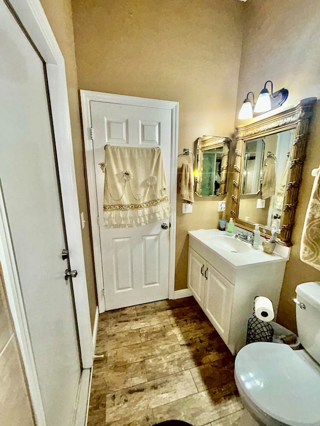 bathroom with hardwood / wood-style flooring, vanity, and toilet