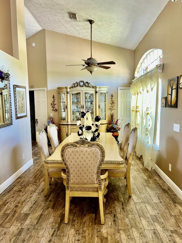 dining area with hardwood / wood-style flooring, ceiling fan, a textured ceiling, and vaulted ceiling