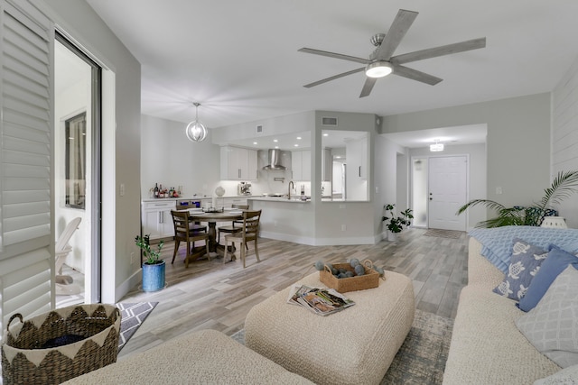 living room featuring sink, light wood-type flooring, and ceiling fan