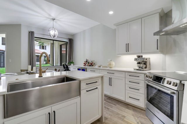 kitchen with wall chimney range hood, electric stove, hanging light fixtures, light hardwood / wood-style floors, and white cabinets