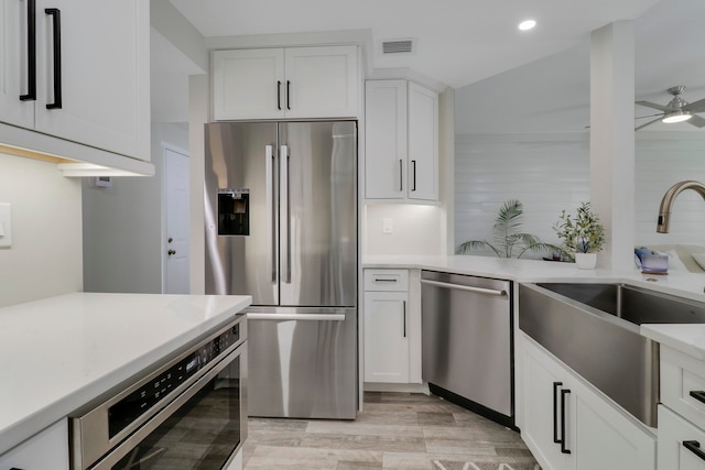 kitchen featuring stainless steel appliances, sink, white cabinets, light hardwood / wood-style floors, and ceiling fan