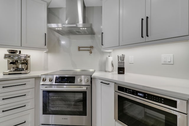 kitchen featuring appliances with stainless steel finishes, wall chimney exhaust hood, and white cabinets