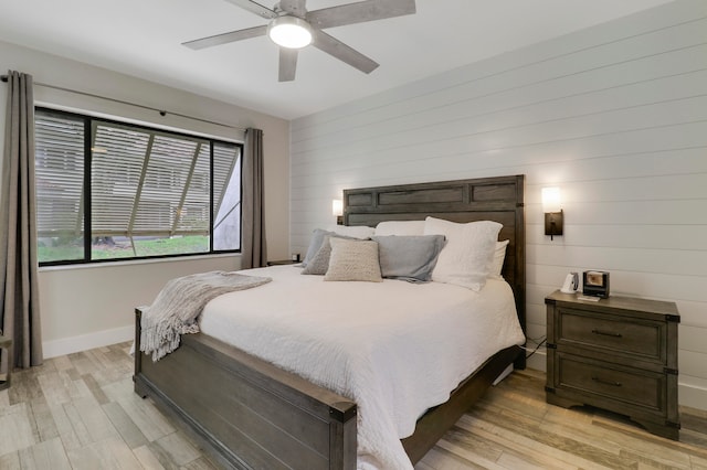 bedroom featuring ceiling fan, wood walls, and light wood-type flooring