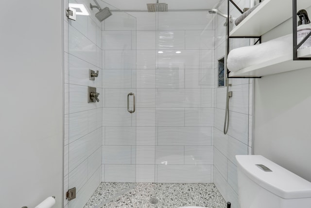 bathroom featuring a shower with door and toilet