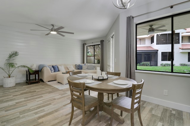 dining room featuring wooden walls, light hardwood / wood-style flooring, and ceiling fan