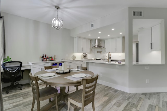 dining room with an inviting chandelier, sink, and light wood-type flooring