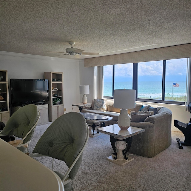 carpeted living room featuring a water view, ceiling fan, plenty of natural light, and a textured ceiling