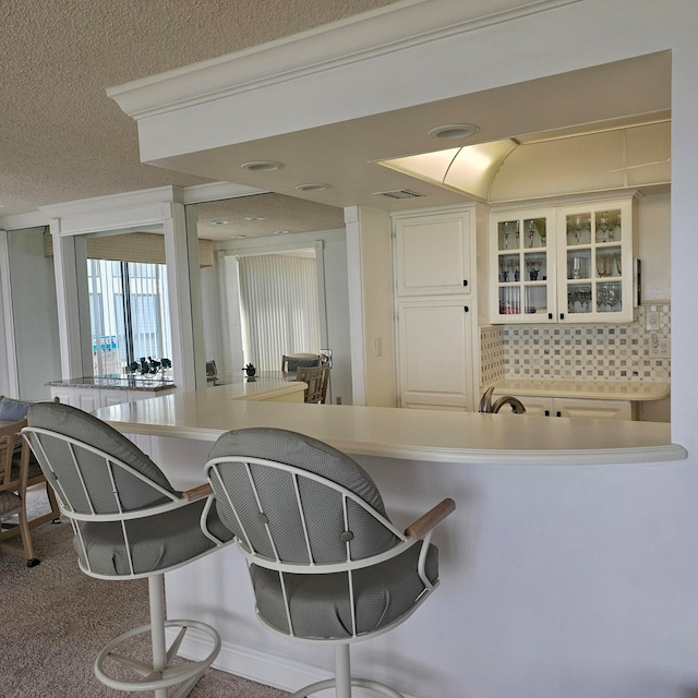 kitchen with decorative backsplash, a textured ceiling, a kitchen bar, and carpet floors