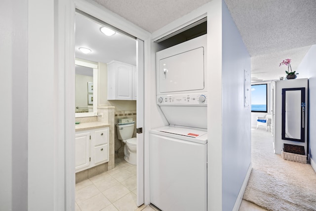 laundry area featuring light colored carpet, a textured ceiling, and stacked washer / dryer