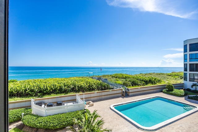 view of swimming pool with a water view and a patio area