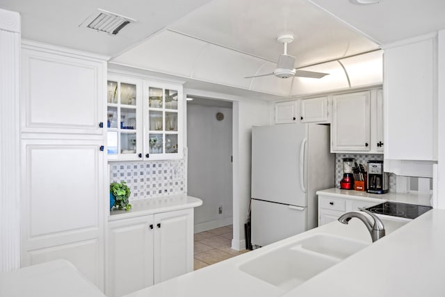 kitchen with white refrigerator, sink, white cabinets, backsplash, and ceiling fan