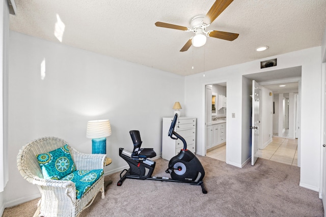 workout area with light carpet, a textured ceiling, and ceiling fan