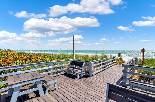 wooden deck featuring a water view and a beach view