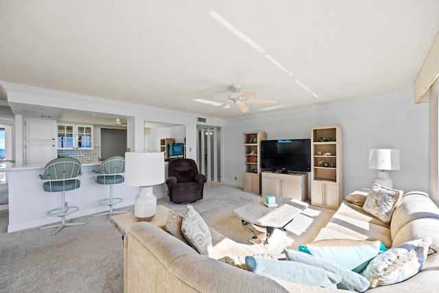 living room with ceiling fan, light colored carpet, a textured ceiling, and crown molding