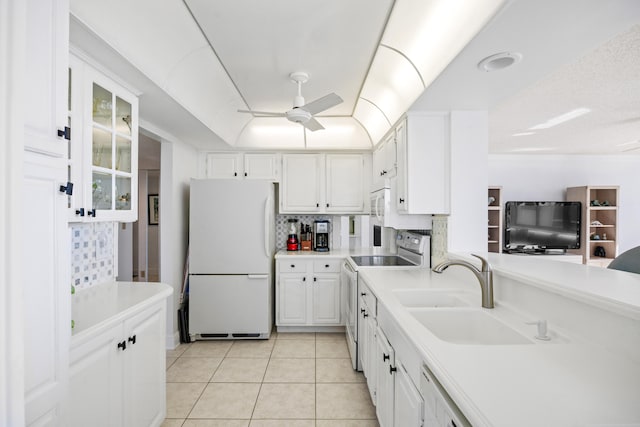 kitchen featuring white refrigerator, light tile patterned flooring, sink, stainless steel range with electric cooktop, and white cabinets