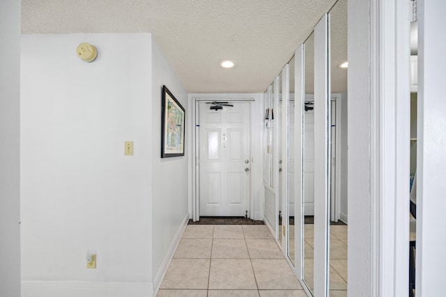 corridor featuring a textured ceiling and light tile patterned floors