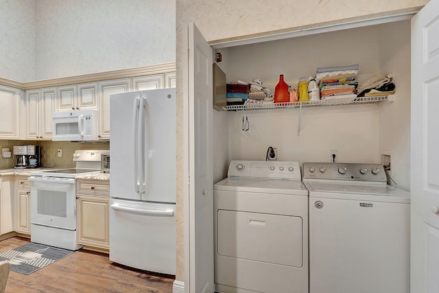 laundry room with washing machine and clothes dryer and light hardwood / wood-style floors