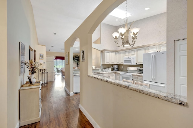 kitchen with pendant lighting, white appliances, a chandelier, dark hardwood / wood-style flooring, and light stone countertops