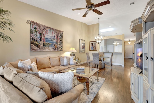 living room with a textured ceiling, dark wood-type flooring, and ceiling fan with notable chandelier