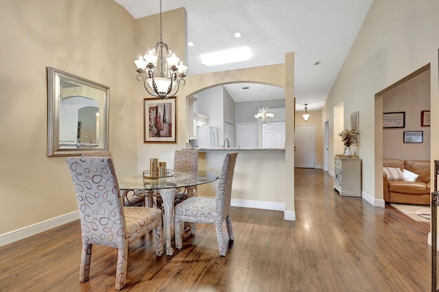 dining area with a towering ceiling, sink, a chandelier, and dark hardwood / wood-style flooring