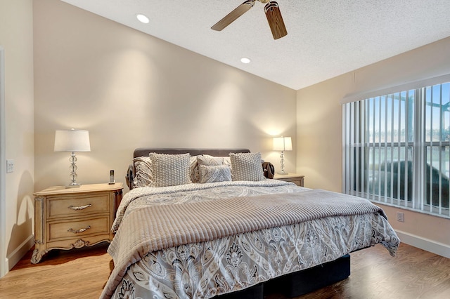 bedroom with lofted ceiling, ceiling fan, light hardwood / wood-style floors, and a textured ceiling