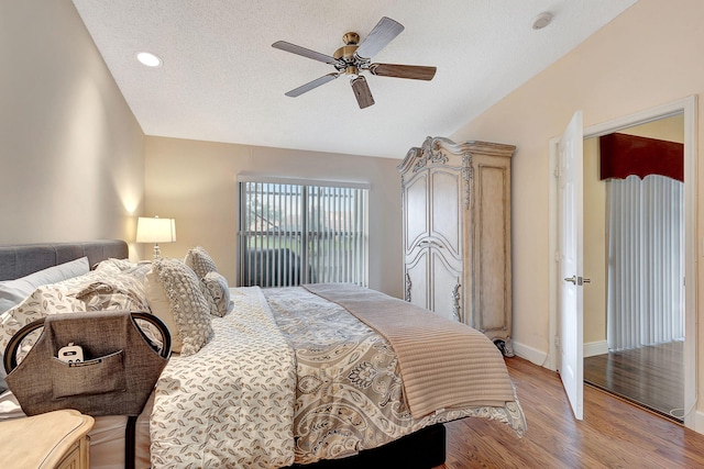 bedroom featuring light wood-type flooring, ceiling fan, and a textured ceiling