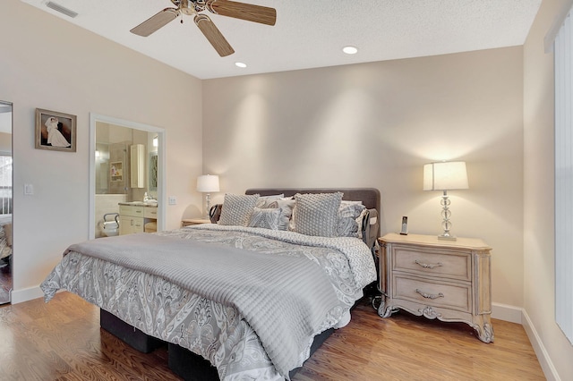 bedroom with ceiling fan, connected bathroom, a textured ceiling, and light hardwood / wood-style flooring