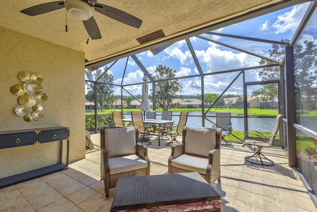 view of patio / terrace featuring glass enclosure, a water view, and ceiling fan