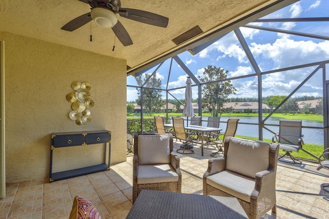 sunroom featuring ceiling fan and a water view