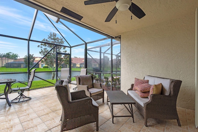 view of patio with glass enclosure, ceiling fan, and a water view