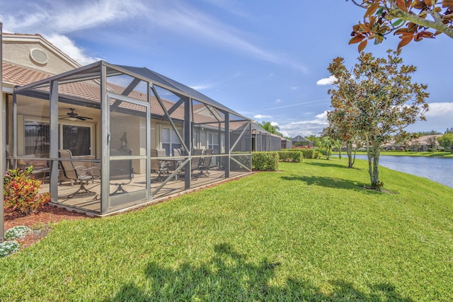 view of yard with glass enclosure, ceiling fan, a patio area, and a water view