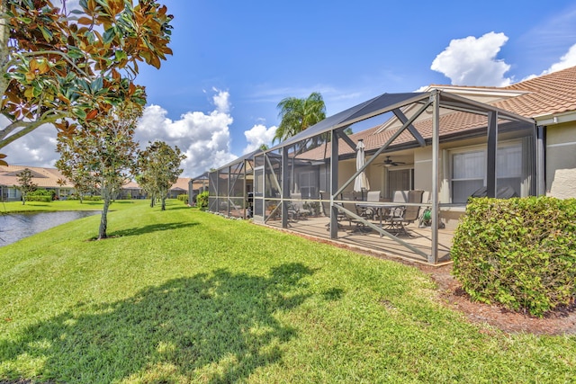 view of yard featuring glass enclosure, ceiling fan, a patio, and a water view