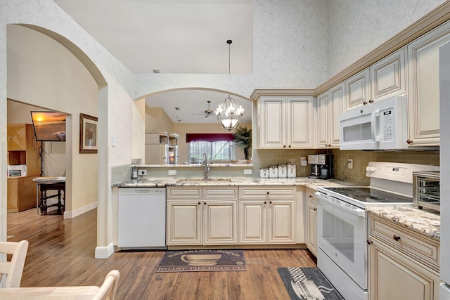 kitchen featuring white appliances, decorative light fixtures, sink, and light hardwood / wood-style floors