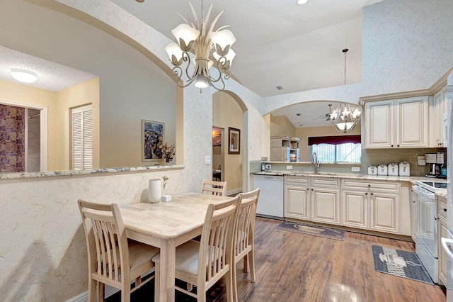 dining room with vaulted ceiling, sink, dark wood-type flooring, and a notable chandelier