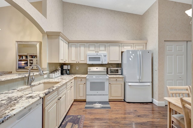 kitchen featuring light stone countertops, white appliances, cream cabinets, hardwood / wood-style floors, and sink