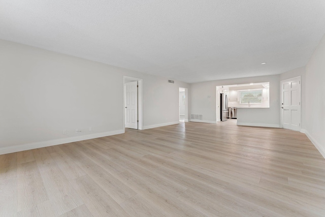 unfurnished living room featuring a textured ceiling and light hardwood / wood-style flooring