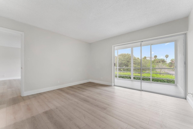 spare room featuring light hardwood / wood-style floors and a textured ceiling