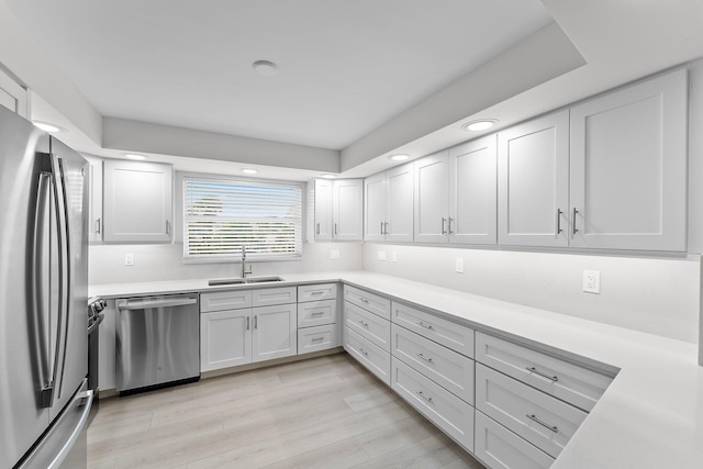 kitchen featuring light wood-type flooring, stainless steel appliances, white cabinetry, and sink