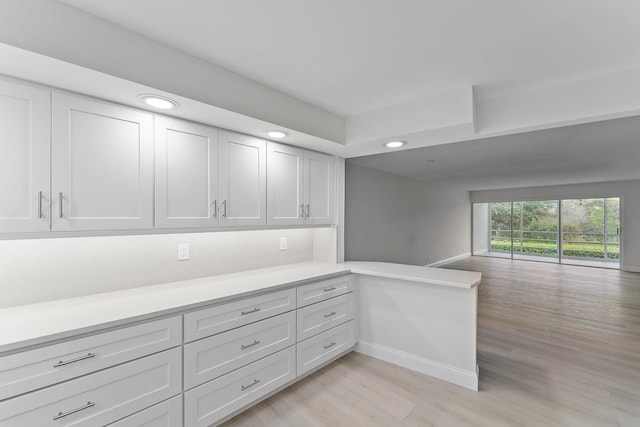 kitchen with kitchen peninsula, light wood-type flooring, and white cabinets