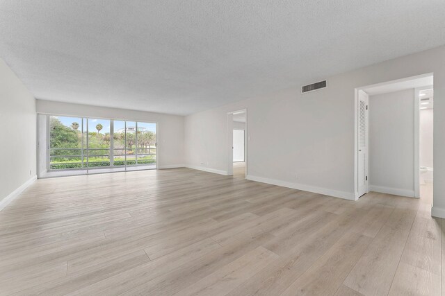 spare room featuring light wood-type flooring and a textured ceiling