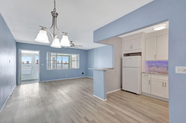 kitchen with white refrigerator, white cabinets, and light hardwood / wood-style floors