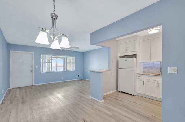 kitchen with white cabinets, backsplash, decorative light fixtures, light hardwood / wood-style floors, and white fridge