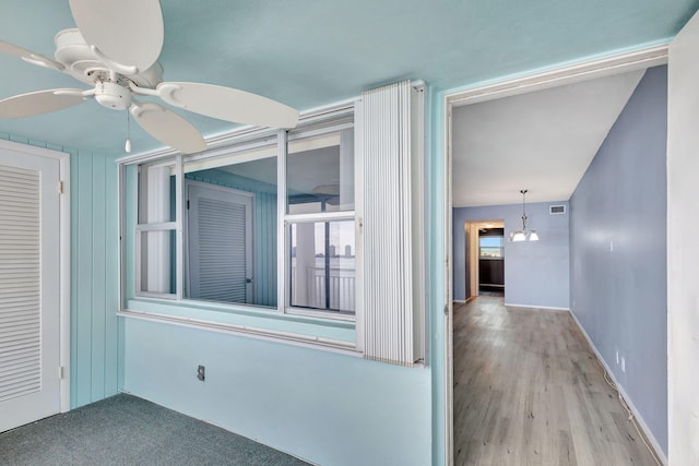 empty room featuring light wood-type flooring and ceiling fan with notable chandelier