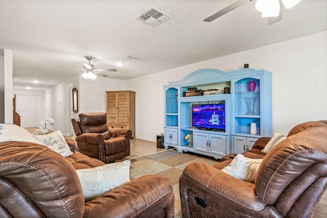 living room with a textured ceiling, ceiling fan, and light hardwood / wood-style floors