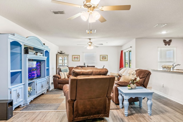 living room featuring ceiling fan, hardwood / wood-style flooring, sink, and a textured ceiling