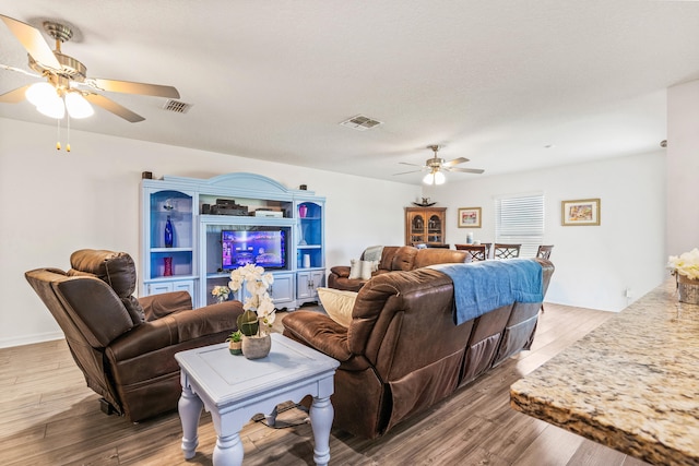 living room featuring a textured ceiling, hardwood / wood-style floors, and ceiling fan