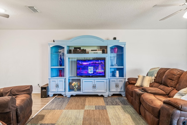 living room featuring a textured ceiling, ceiling fan, and light wood-type flooring