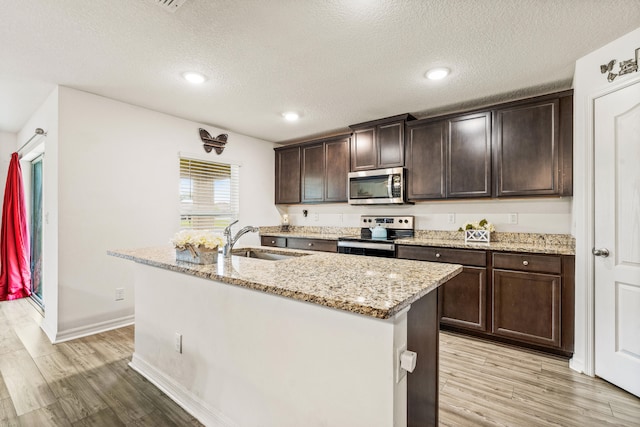 kitchen with light hardwood / wood-style flooring, appliances with stainless steel finishes, a textured ceiling, and sink